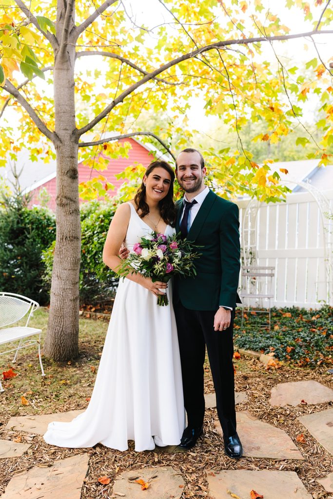 bride wearing her dress from Savvys bridal in Kansas City and holding purple and white roses from the Flower Lady with the groom wearing an emerald green suit jacket