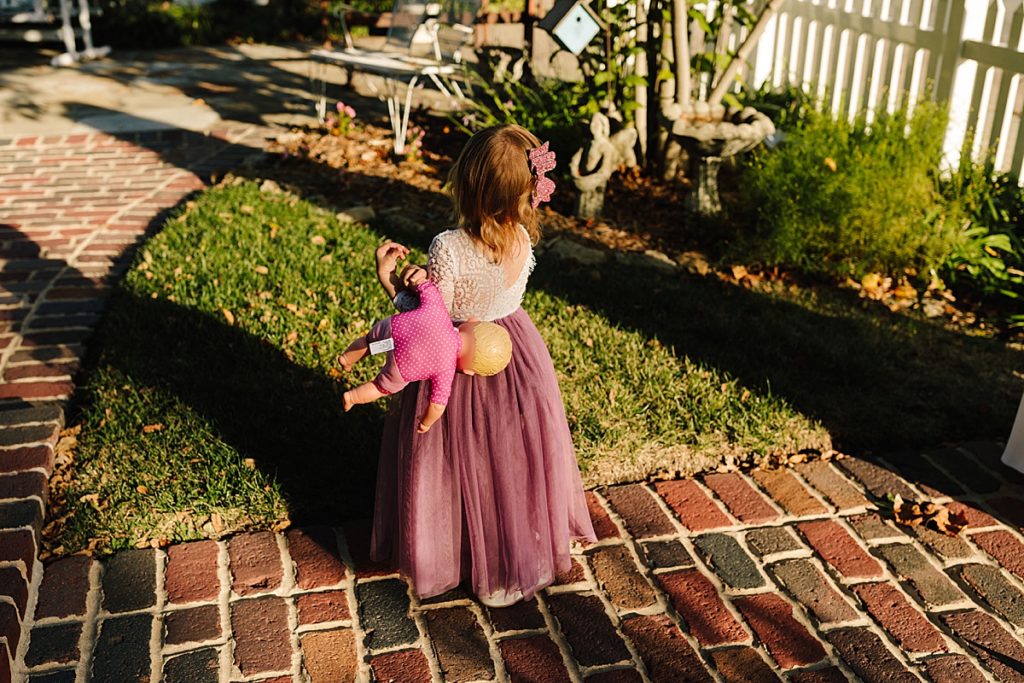 flower girl plays with her doll before the wedding ceremony starts