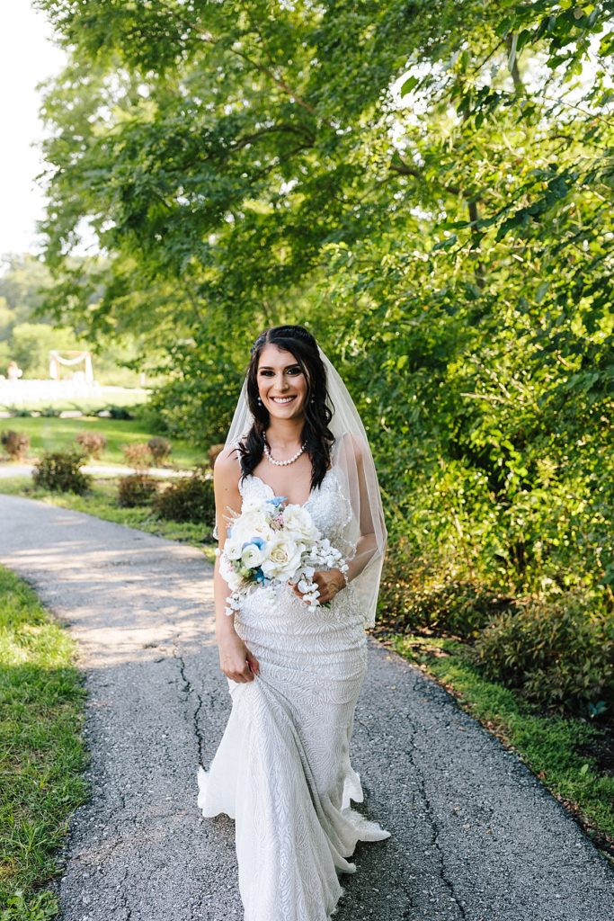 blushing bride with blue and white floral bouquet at her kansas city wedding photographed by natalie nichole photography