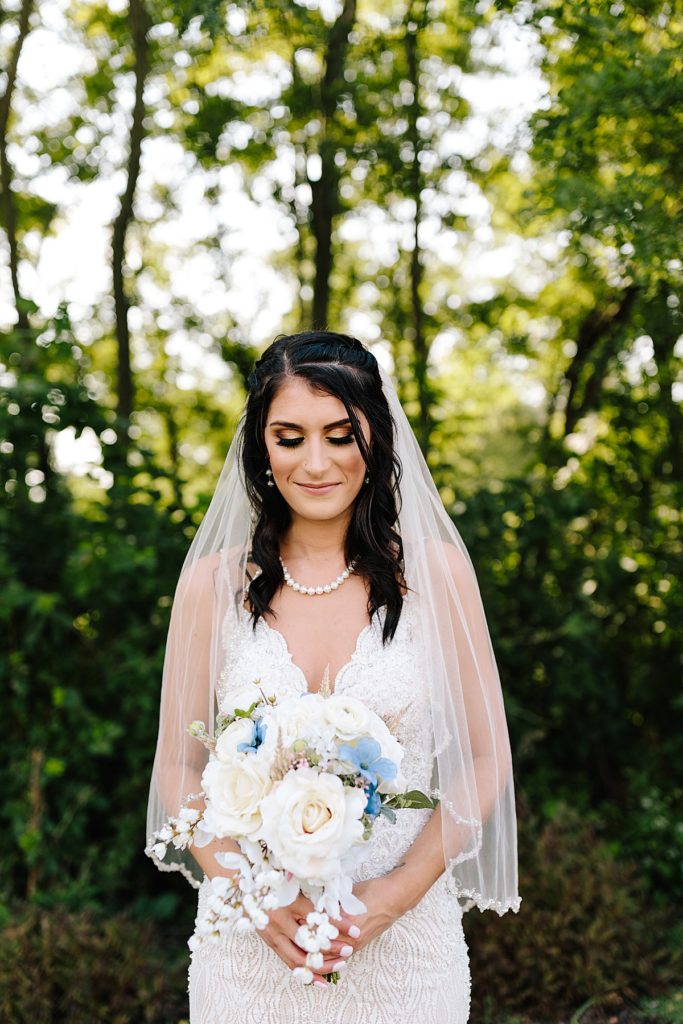 bride's attire, beaded lace wedding dress from stephanie's bridal paired with a traditional veil with beading, DIY bouquet with white roses and blue accents