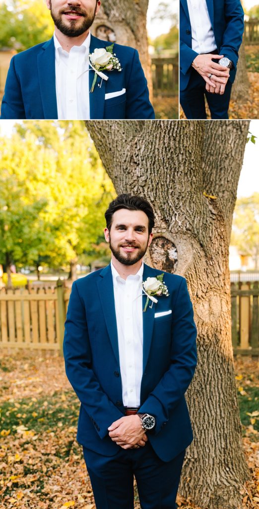 groom wearing a navy suit, a white shirt, and a brown watch at a fall wedding with a white rose boutonniere, before his October wedding ceremony at Raintree Lake in Kansas City. fall wedding color palette,