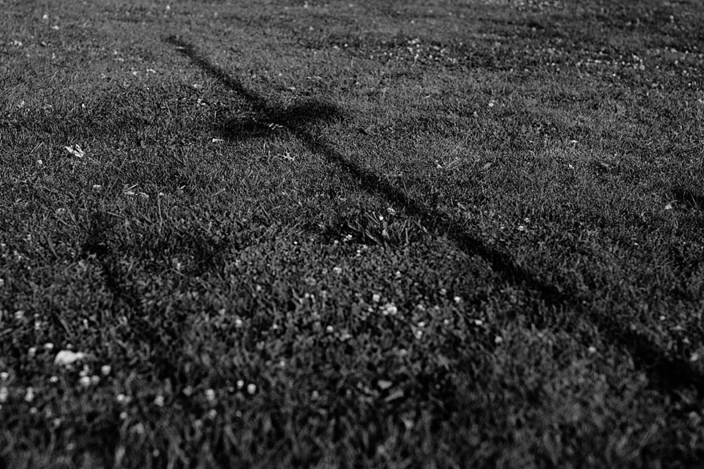 wooden cross casts shadow in the grass at sunset intimate elopement wedding ceremony,