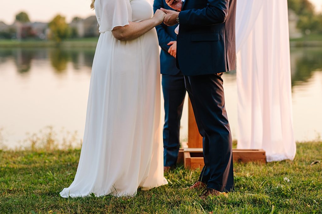 bride and groom sun set outdoor wedding ceremony, groom in navy suit bride in flowy dress