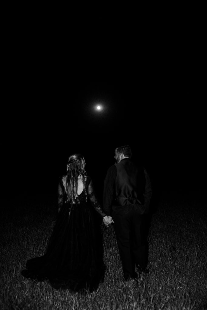 kansas city wedding photographer, after dark photos, bride and groom with the full moon after their halloween wedding, bride wearing black lace wedding dress, groom wearing all black suit, groom attire, night time wedding portraits, flash wedding photography, spooky wedding photography ideas, halloween wedding inspo