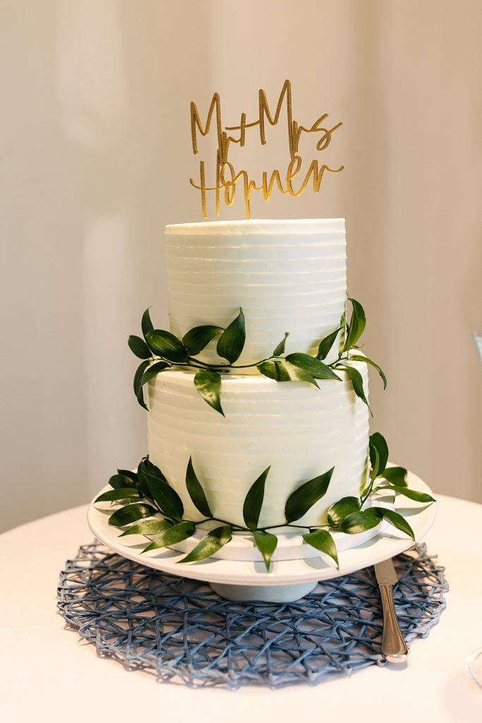 classic wedding cake, gold cake topper, white icing, white cake with greenery, simple wedding cake