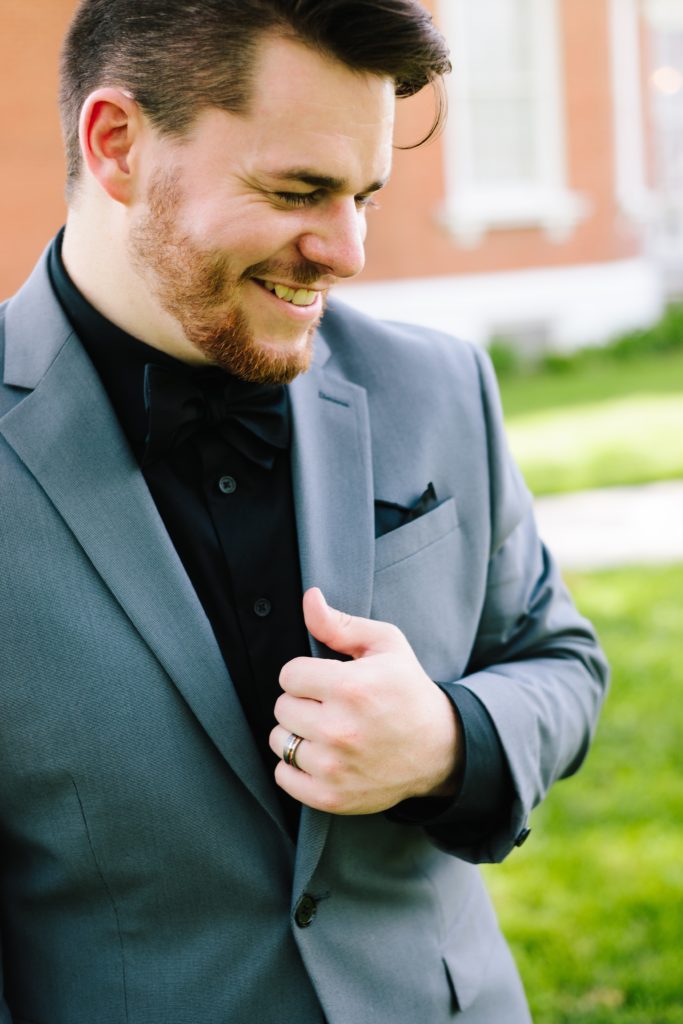 Handsom groom in gray suit with black shirt. His black bow tie pulls the whole look together.