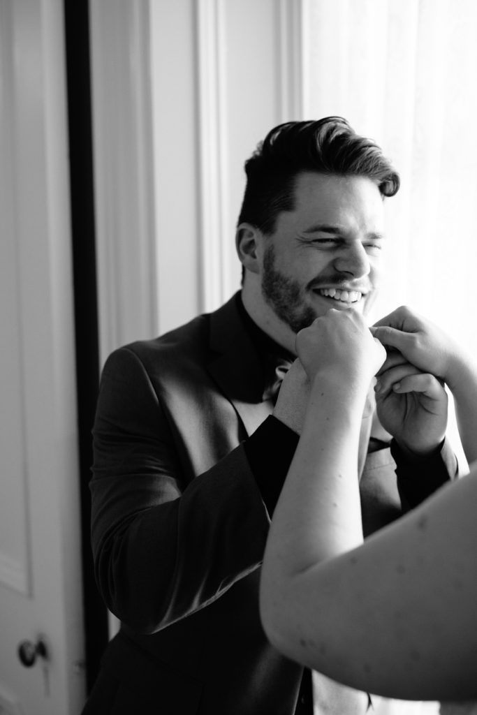smiling groom in black and white