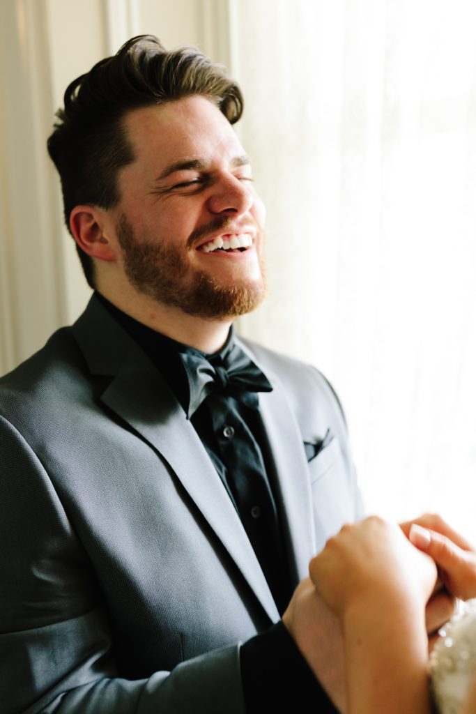 Groom holding brides hands and smiling