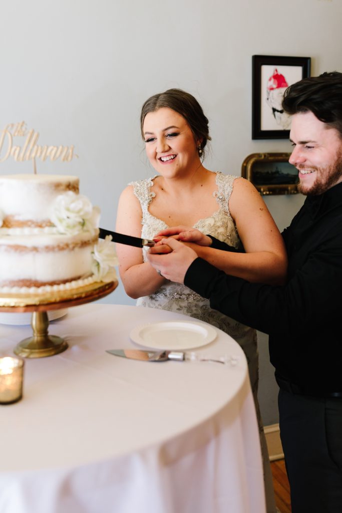 bride and groom cutting the cake | naked cake with white flowers and wood lettering topper