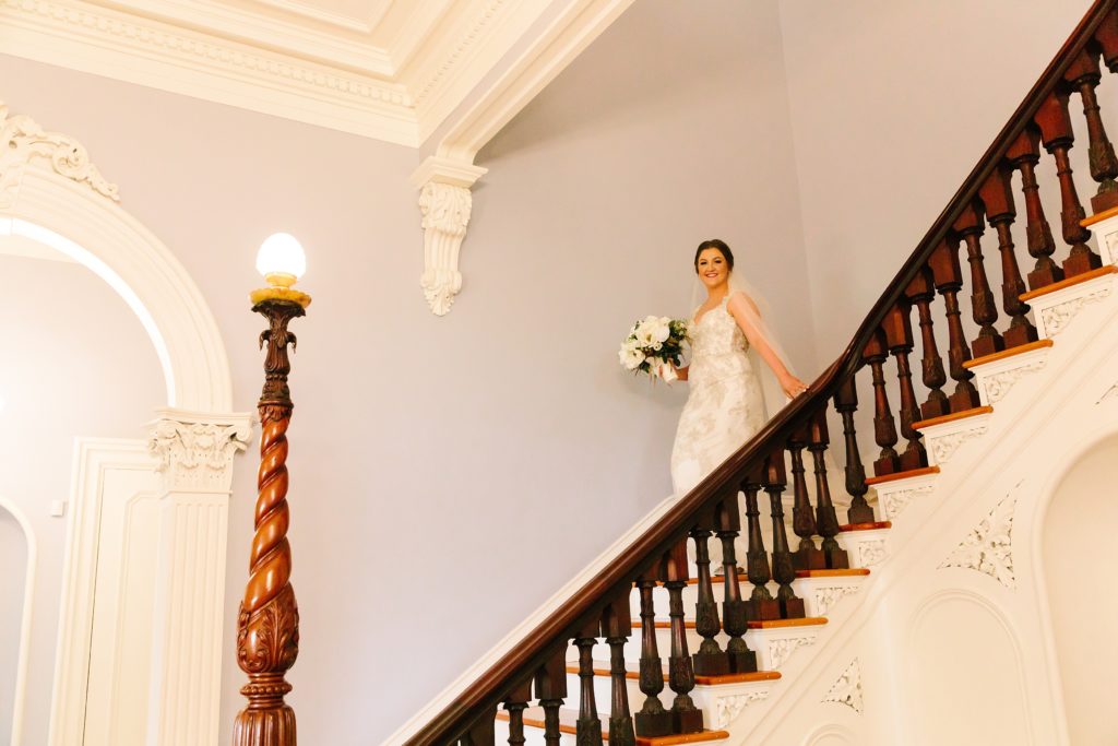 bride walking down grand staircase before wedding ceremony
