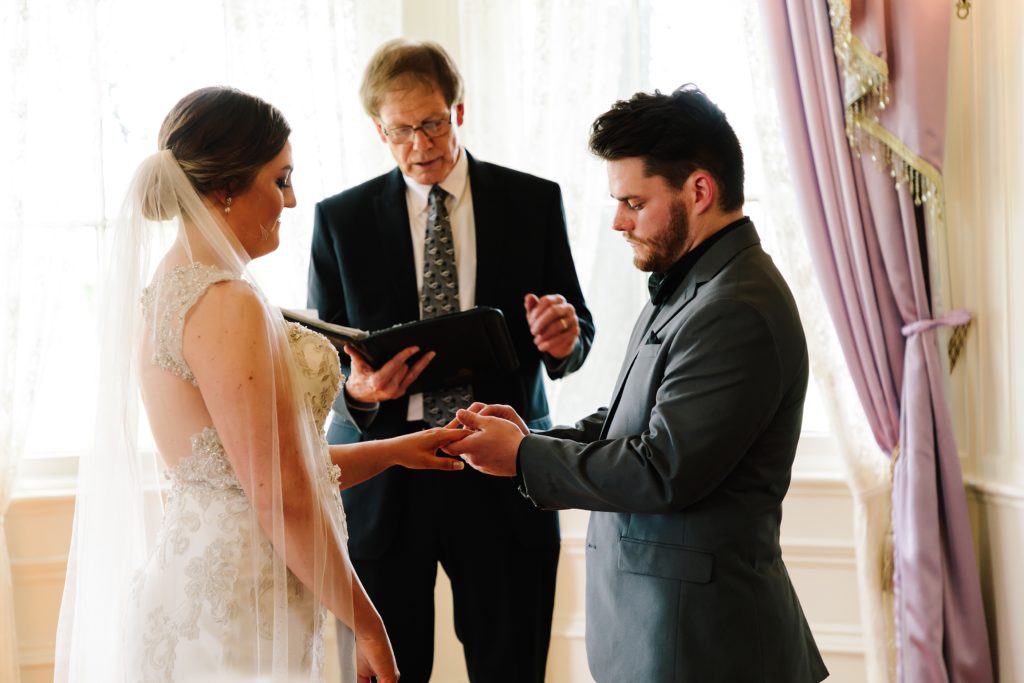 groom gives bride her wedding band during intimate coronavirus wedding