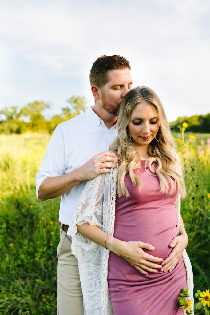 sunrise maternity session at Shawnee Mission Park, Kansas City Photographer, classic maternity pose ideas, she is holding belly, him kissing her head, warm light, golden hour, bright and airy, colorful, true to color