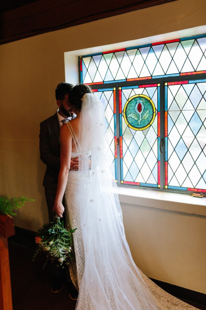 dramatic photo of bride and groom, stain glass window, church wedding, traditional wedding ceremony, religious wedding ceremony, unity candle, modest bride