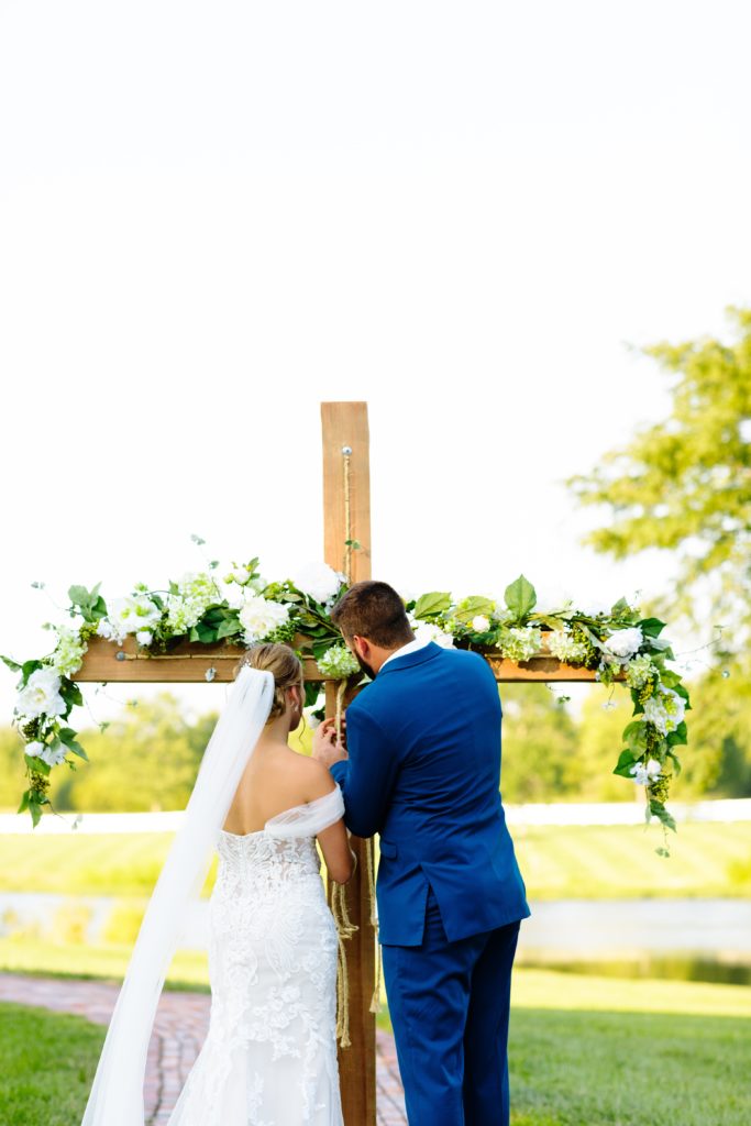 Summer Wedding at Mildale Farm, Natalie Nichole Photography, Kansas City Wedding Photographer, blue and white wedding, anemone, navy, summer wedding color palette, shades of blue, boutonniere, blue suits, generation tux, wedding dress, sunset wedding, kansas city wedding, unity ceremony, unity braid ceremony, commitment ceremony, wooden cross, the little clover, cross with garland, outdoor wedding, wedding ceremony outside