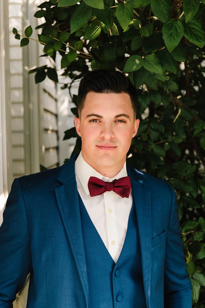 groom in navy suit with maroon bow tie, blue suit, bow tie, red, maroon, grooms attire, grooms wedding day look
