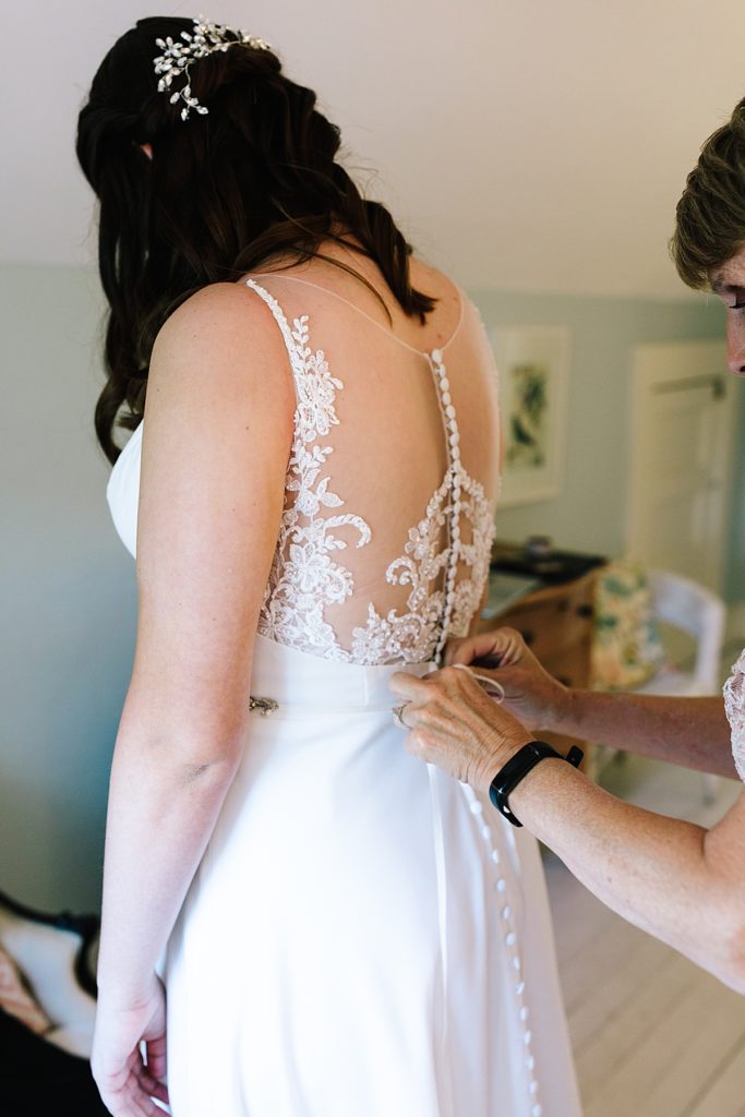 mother of the bride helps button daughters wedding dress from Savvy's bridal in Kansas City