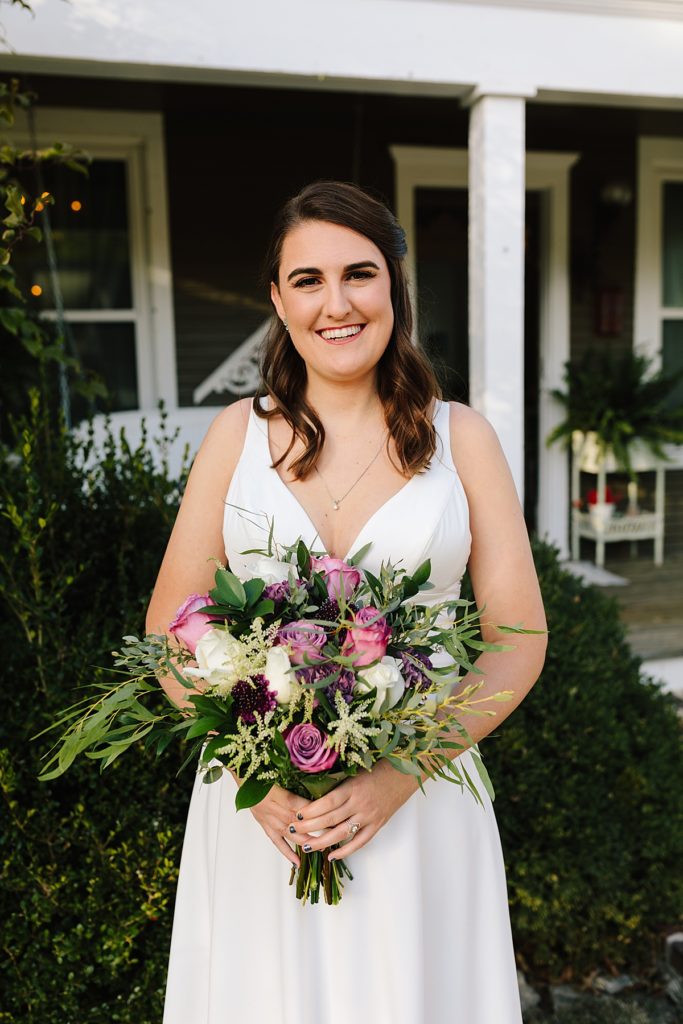 gorgeous modern bride wearing an a-line dress from savvy's bridal holding her purple and white boho bouquet