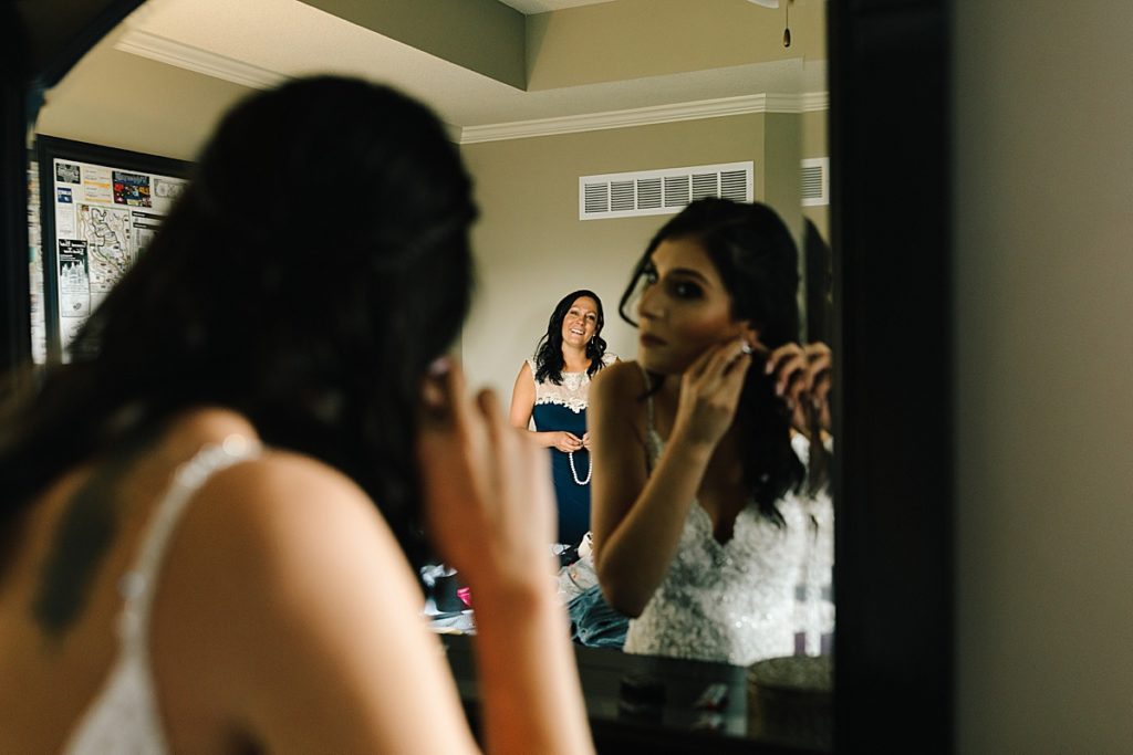 brides mom watches her put on her pearl earrings on her wedding day