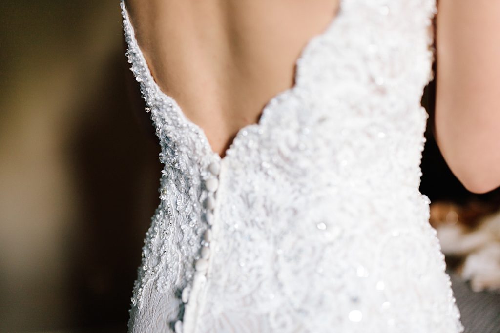 details of a lace wedding dress from stephanie's bridal in independence Missouri, buttons down the back and beaded detail
