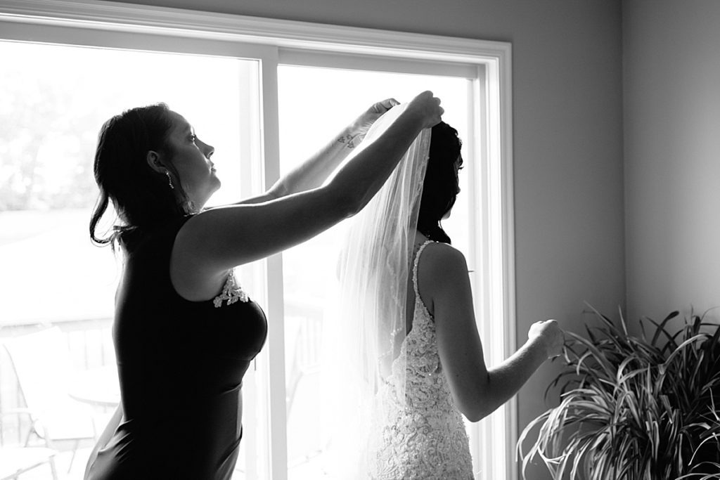 brides mom puts her wedding veil in brides hair, veil has beaded edge