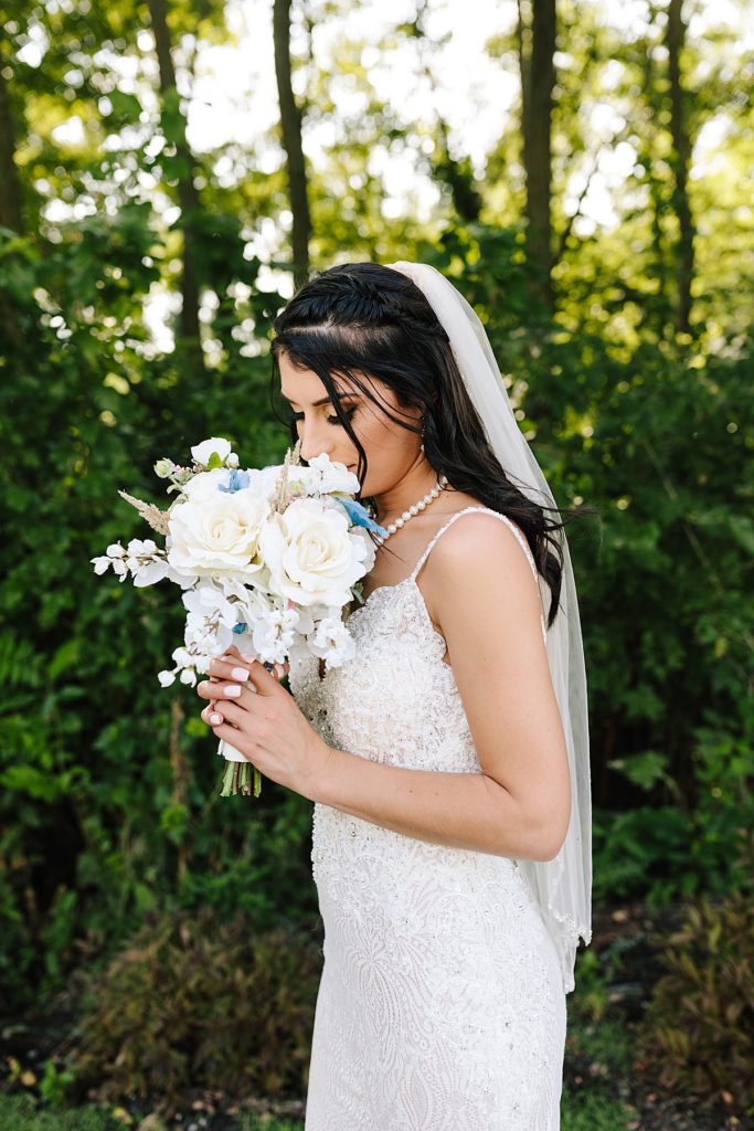 vintage inspired bride smelling her lush white rose bridal bouquet while wearing her lace sleeveless mermaid wedding dress