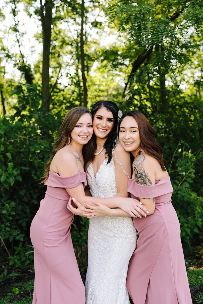 bride with two bridesmaids wearing pink off the shoulder dresses