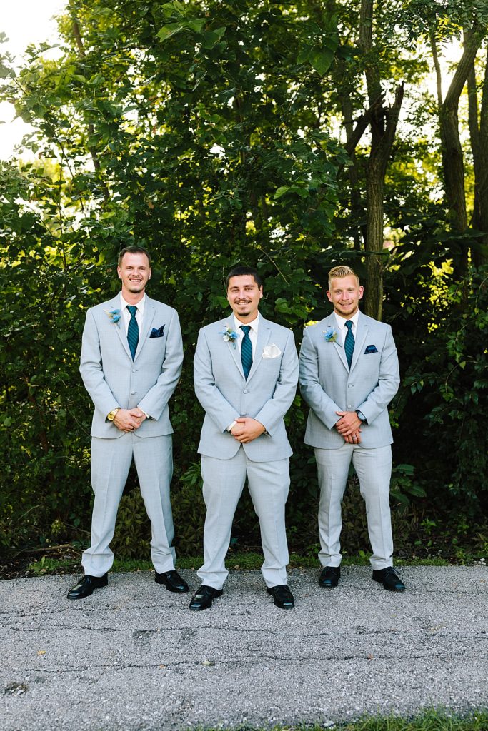 groom with his two groomsmen in gray suits with navy ties