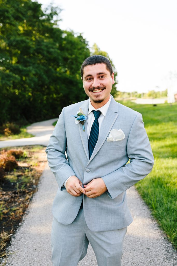 smiling groom on his wedding day wearing a grey suit jacket and navy tie, excited to get married at Stoney Creek Hotel in Kansas City