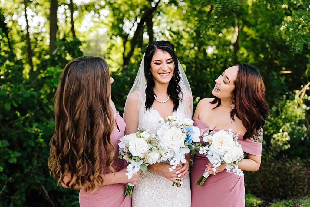bride laughs with her two bridesmaids before her summer wedding in kansas city