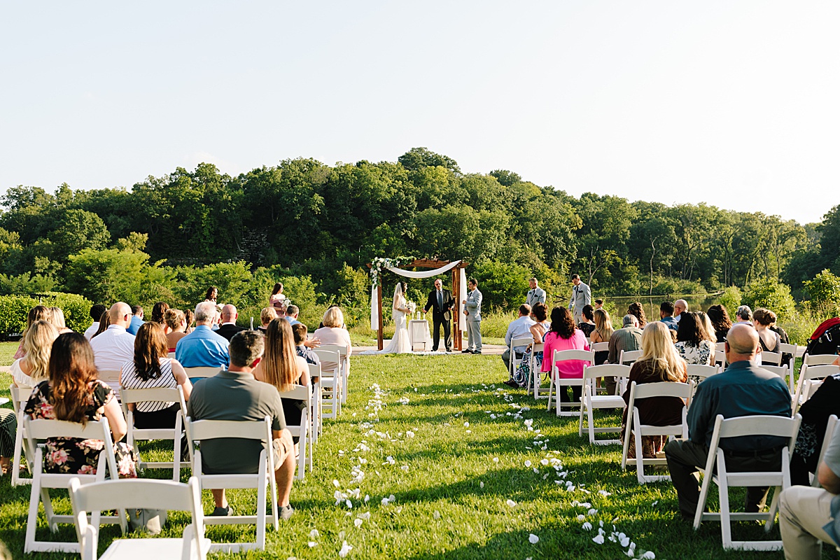 summer outdoor wedding ceremony at Stoney Creek Hotel in independence Missouri, lush green trees and golden hour make a beautiful kansas city wedding