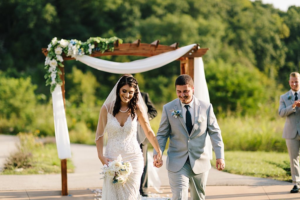 bride and groom smiling after wedding ceremony and walking back up the aisle ready for their backyard wedding reception