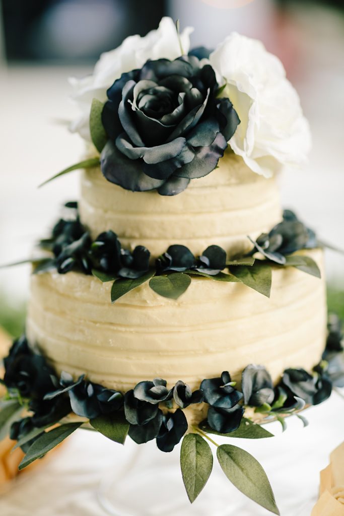 simple two layer wedding cake with blue and white flowers and greenery