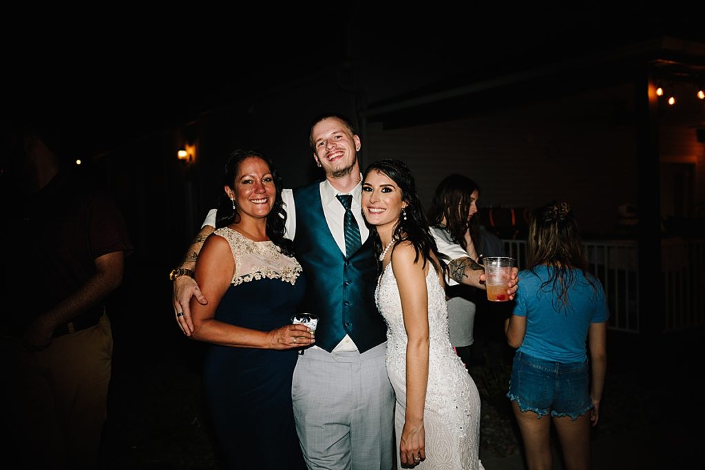 bride with her brother and mom at their backyard wedding reception in Kansas City