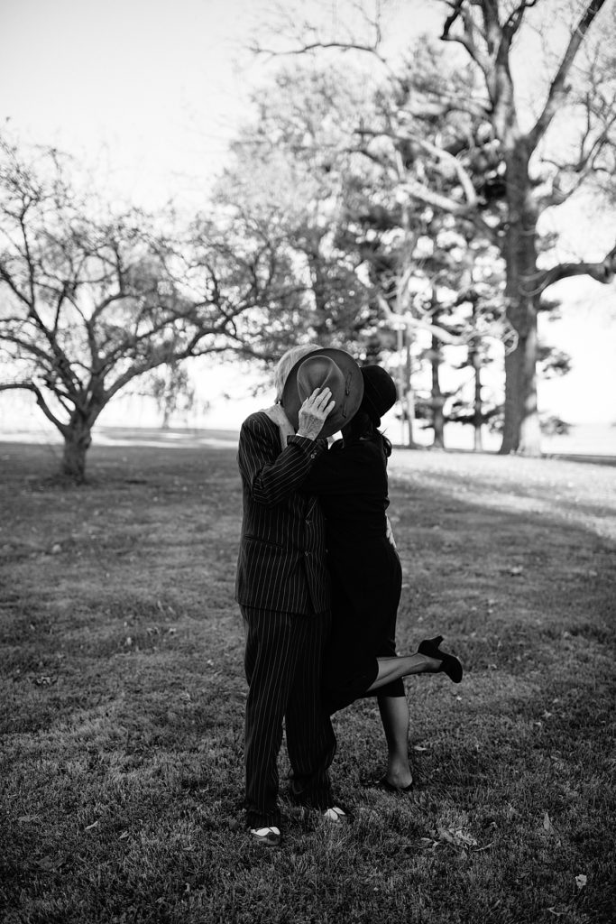 Retro 1920's inspired photoshoot in Lexington Missouri by Kansas City Photographer Natalie Nichole Photography. Couple kisses behind gentleman's hat
