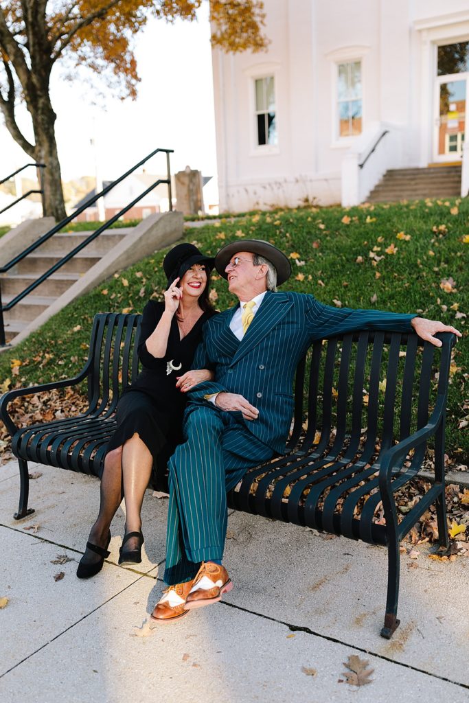 couple poses for 1920's inspired photoshoot on a bench