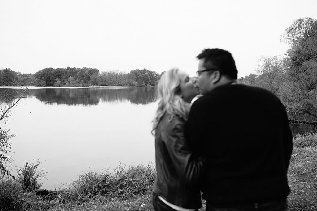 black and white photo of couple kissing by the lake at James A Reed Memorial Wildlife Area in Kansas City