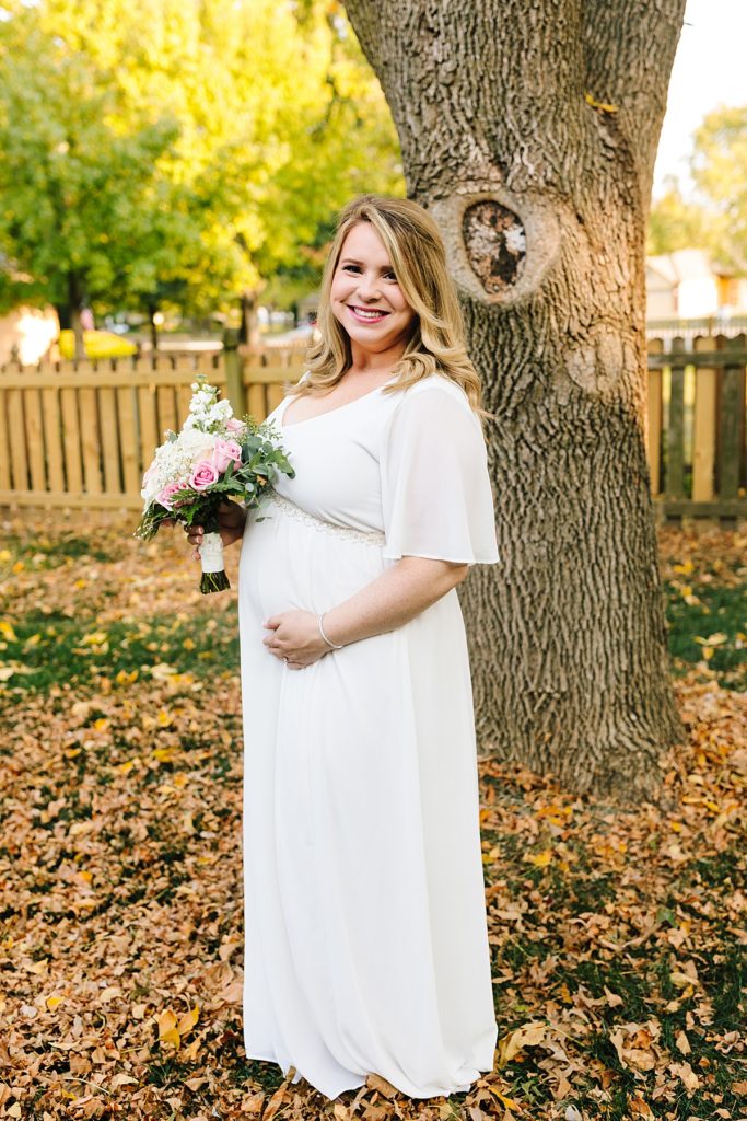 pregnant bride in a simple modern wedding dress with flowy sleeves at her intimate fall wedding elopement