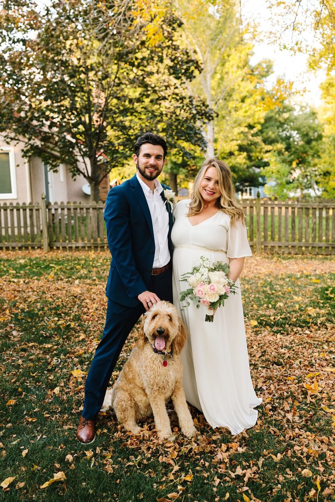 bride and groom with their golden doodle dog in their backyard before their fall wedding ceremony and intimate elopement in October, how to incorporate your dog into your wedding