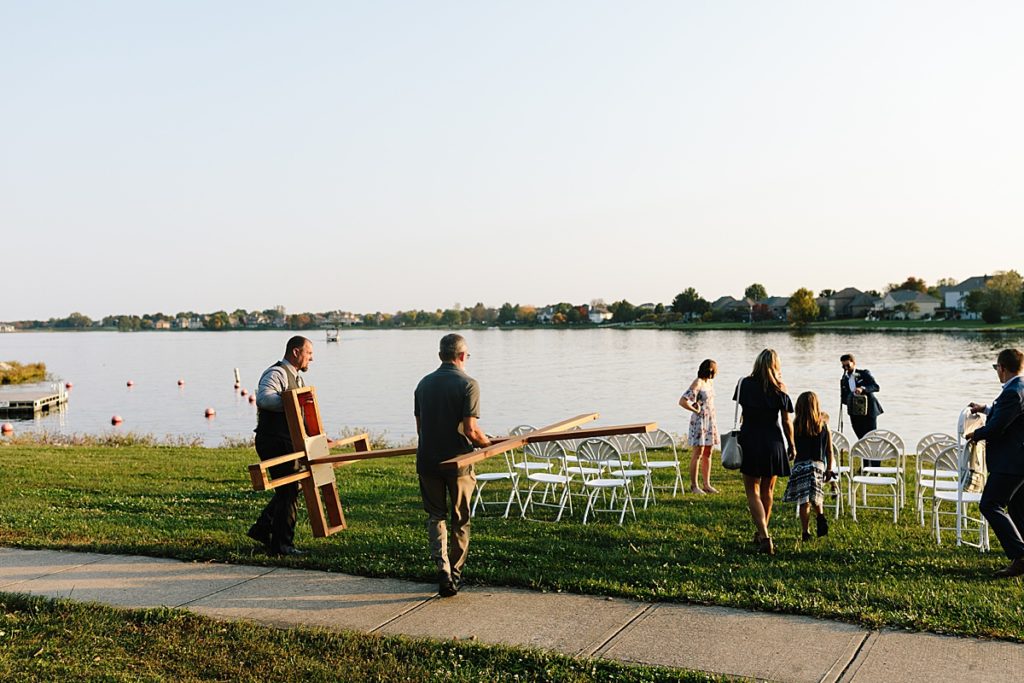 wedding guests set up handmade wooden cross at intimate wedding ceremony for a fall elopement during sunset at Raintree Lake
