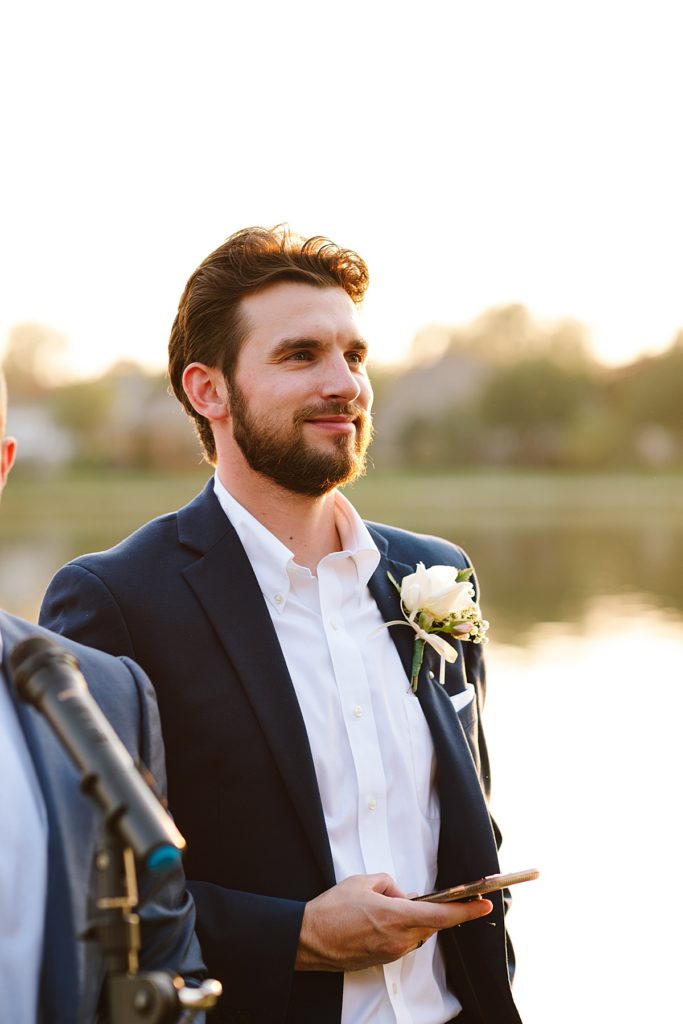 groom at the end of the aisle waiting for his wife at golden hour in october at their at home wedding ceremony