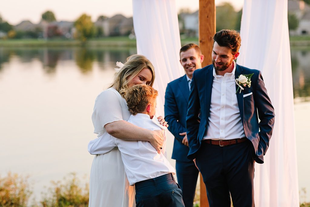 ring bearer hugs his new step mom at his dads wedding ceremony