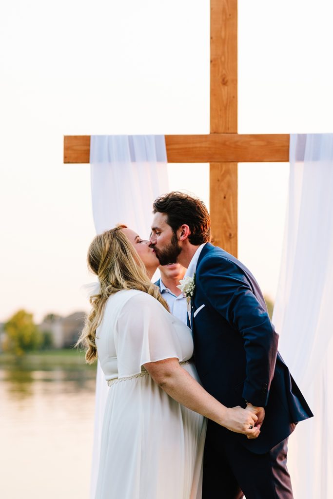bride and groom kiss for the first time as a married couple at their intimate outdoor elopement on the lake in kansas city