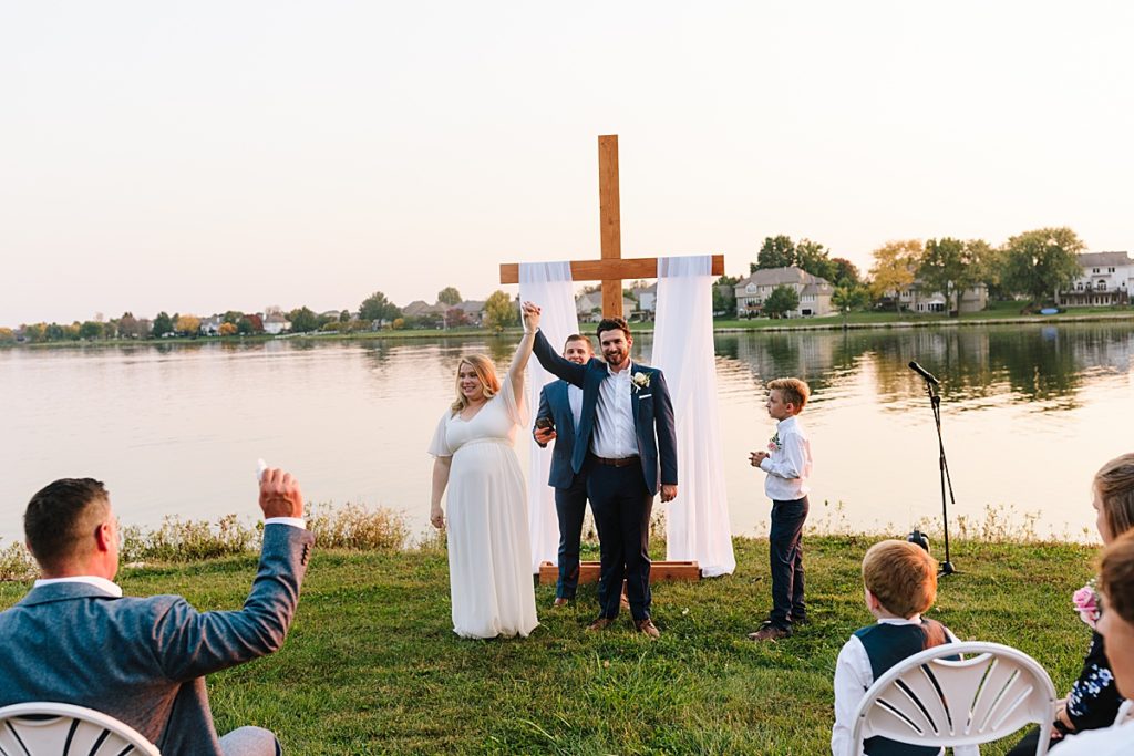 bride and groom celebrate their marriage right after their intimate outdoor wedding elopement on raintree lake in kansas city