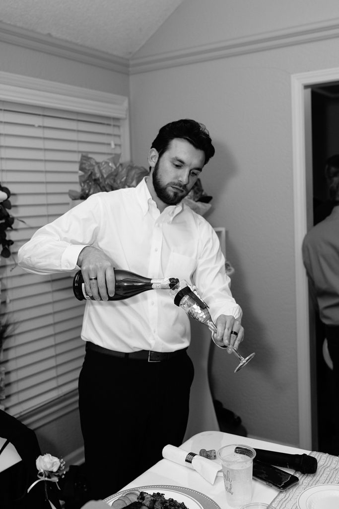 From a Large Wedding to an Intimate Elopement at home groom pours champagne to celebrate