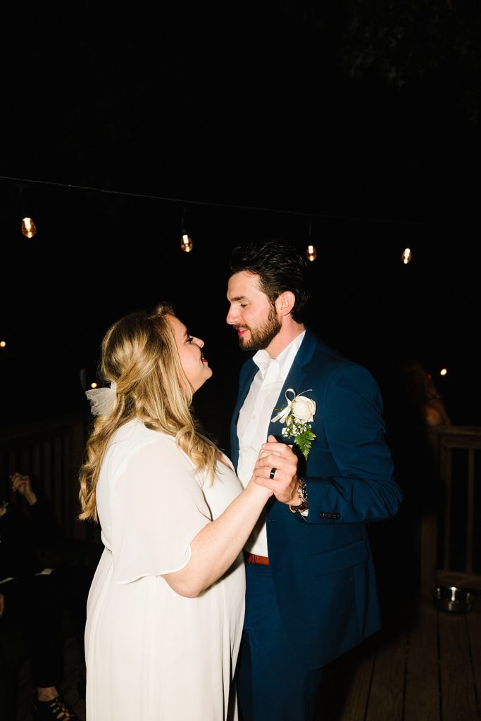 From a Large Wedding to an Intimate Elopement at home bride and groom have their first dance on the deck in the backyard under twinkle lights in kansas city