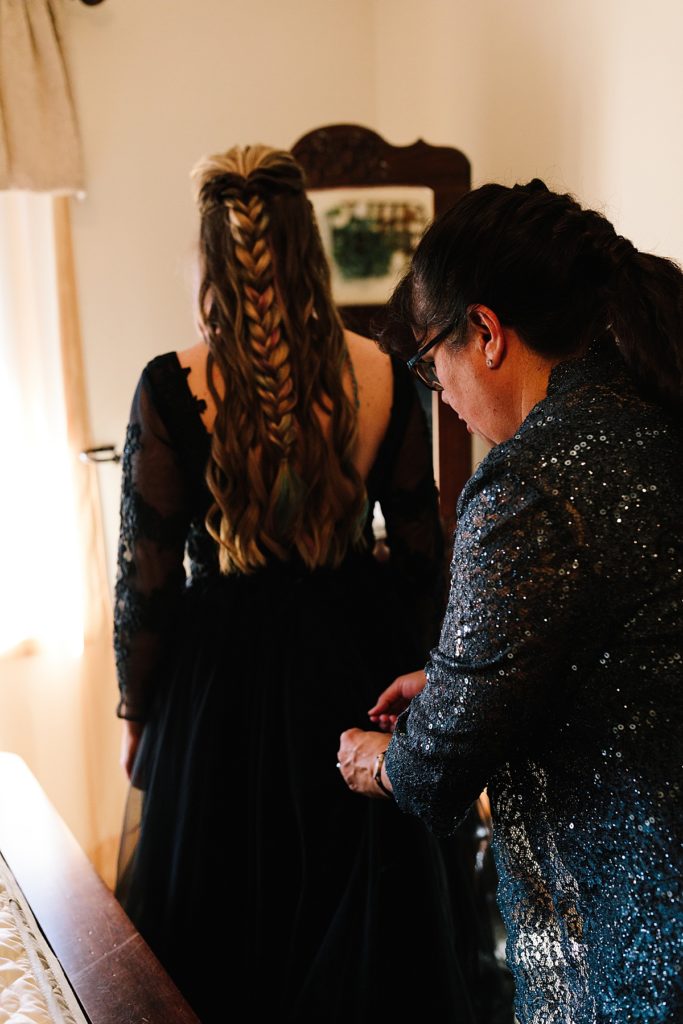 brides mom helping her get ready on her wedding day in a black wedding dress