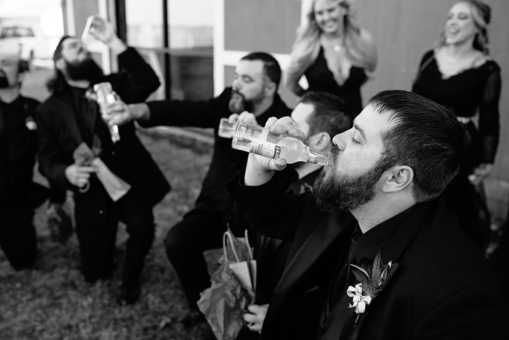 bridesmaids ice the groomsmen at halloween wedding, groom finishes his smirnoff ice