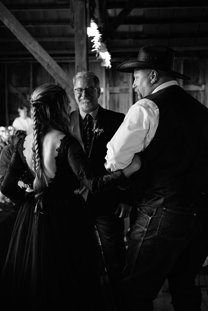 bride walks down the aisle with her dad and her step dad at halloween wedding