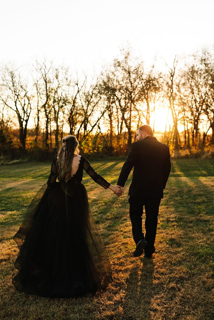must have photos at your halloween wedding, black long sleeve wedding dress, all black suit, bride with half up braid, golden hour sunset husband and wife portraits, kansas city wedding