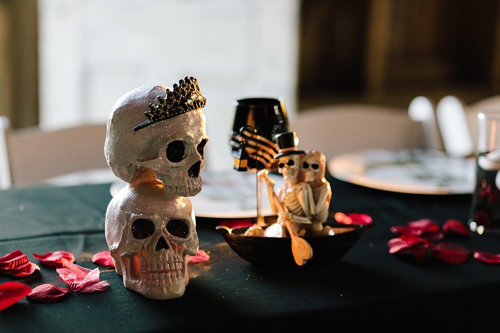 halloween wedding inspiration, halloween decor, skulls, skeletons, black table cloth and red rose petals,